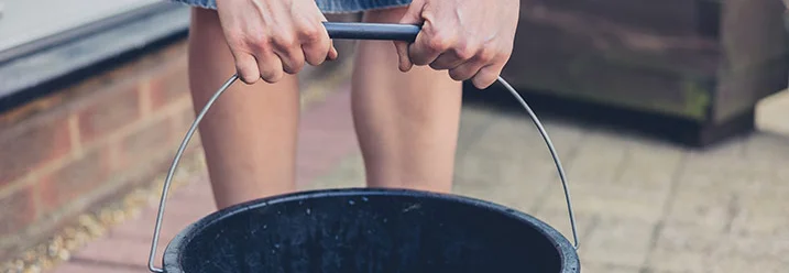 Person hält schwarzen Eimer